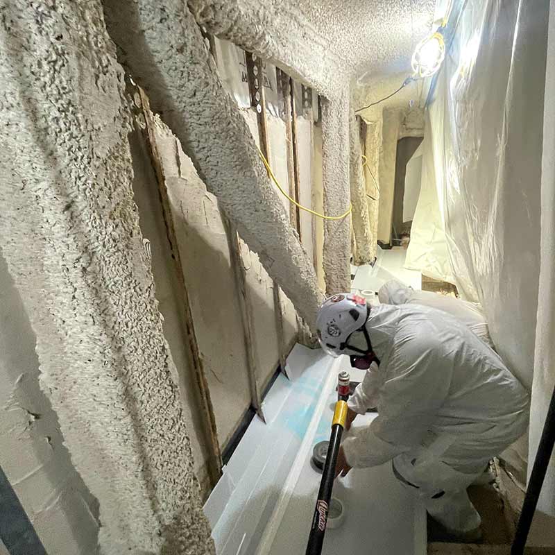 Protected technician completing asbestos removal inside the healthcare facility